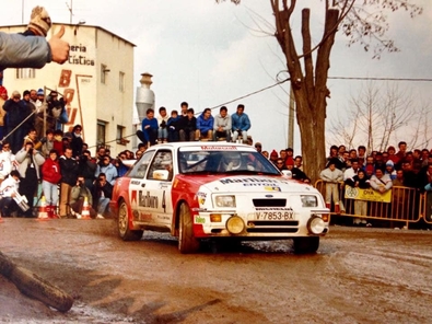 Carlos Sainz - Antonio Boto
35º Rally Costa Brava 1987. Ford Sierra RS Cosworth (V-7853-BX). Abandonó por la rotura de la transmisión.

Polémica en torno a Sainz
Corrió cómo un reguero de pólvora la voz de que Sainz había sufrido un incidente con dos coches que venían de cara en pleno tramo, un vehículo de la Guardia Civil y otro de la organización, colisionando con uno de ellos.

Carmelo Ezpeleta, director del equipo Race-Marlboro, pedía la anulación del tramo y aseguraba que todo estaba muy claro, filmado desde el helicóptero que permanentemente seguía a Carlos Sainz para obtener tomas televisivas. Pasados los primeros instantes, la versión fue suavizándose, y aunque la organización, en este caso Juan Pons director de carrera, afirmaba que ambos coches estaban parados, Carmelo Ezpeleta aseguró que le habían admitido que bajaban en sentido contrario. lnsinuando una posible reclamación para anular el tramo justo en el momento en el que se supo que Carlos abandonaba definitvamente.

Carlos Sainz realizó una rueda de prensa, alabando la organización y lamentando este punto negro, más que nada porque representaba un grave peligro innecesario, asegurando que rompió la transmisión quizá por el golpe que había dado en la cuneta.

Curiosamente cuando llegó el helicóptero y descendió el cámara de vídeo, se le preguntó sobre el incidente sobre la filmación.
¿Qué incidente? Yo no he visto nada y no he podido filmar nada de esto porque no lo hemos visto. Es más, en el helicóptero nadie ha comentado nada sobre el tema, afirmó “Cherna” González, de Telesport, un cámara que seguía todos los rallyes del Mundial y los mejores de España.

Del 19 al 21 de Febrero, Lloret de Mar, Girona, Catalunya, España.
Superficie: asfalto - tierra.

Al año siguiente la prueba se fusionó con el Rally Catalunya pasando a llamarse Rally Catalunya-Costa Brava, por lo que la edición de 1988 se celebró bajo este nombre.

El Rally tenia un total de 1.139,5 Km con 27 tramos especiales.

Tomaron la salida 106 equipos, finalizaron 51.

© Pepe Santamaria
@
Palabras clave: ;Ford;Sierra;Cosworth;RS;Costa_Brava;1987
